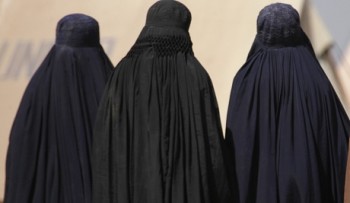 Internally displaced women, fleeing a military offensive in the Swat valley region, walk through the UNHCR Jalozai camp wearing their burqas