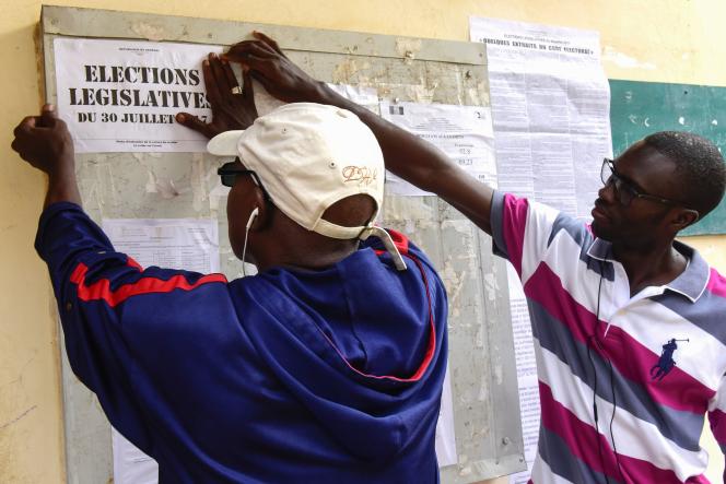 Members of the election commission put up a placard in a polling station during Senegal's legislative election, on July 30, 2017 in Dakar. Senegalese voters cast ballots on July 30 to elect a new parliament, a test run for President Macky Sall ahead of a 2019 presidential election and after a campaign marred by violence and tensions.  / AFP / SEYLLOU