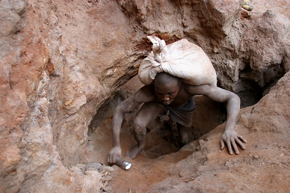 A boy holding a flashlight climbs out of a mining hole, bearing a sack of excavated dirt on his back, in the eastern mining town of Durba in Ituri Province. The dirt is carried to the river in bags, where it is sifted with water to find gold. The mines are only partly functional - some are run by foreign companies or local warlords - but extensive 'artisanal' mining continues, as families and children orphaned by the conflict prospect for gold in abandoned mine sites or in riverbeds. [#6 IN SEQUENCE OF SEVEN]

In 2004 in the north-eastern region of the Democratic Republic of Congo (DRC), fierce fighting continues, part of a six-year conflict in which nearly 4 million Congolese, the majority of them civilians, have died of starvation, violence and disease. Some 6 million people throughout the region are affected by the ongoing conflict, and an estimated 2.5 million have fled their homes.   Relief efforts have been hampered by surges of violence in the resource-rich Ituri Region, as warring militia groups - and outside forces - continue to plunder DRC's gold, diamond and mineral wealth. International NGOs and large mining companies have pulled out for security reasons, leaving company-built towns bereft of basic services. Children who have been orphaned, abandoned or separated from their parents can now be found living on the streets of larger towns like Bunia, where the presence of MONUC (United Nations Organization Mission in the DRC) offers some degree of safety. UNICEF provides health services, educational materials and other supplies to children living in camps for those displaced by the conflict, but there is a pressing need for shelter and protection services for children elsewhere in the region.